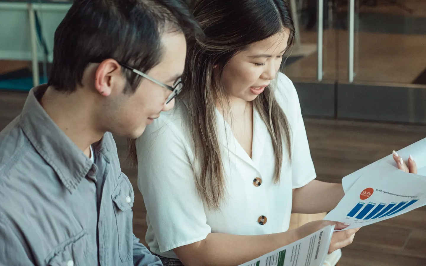 Two colleagues comparing documents in an office.