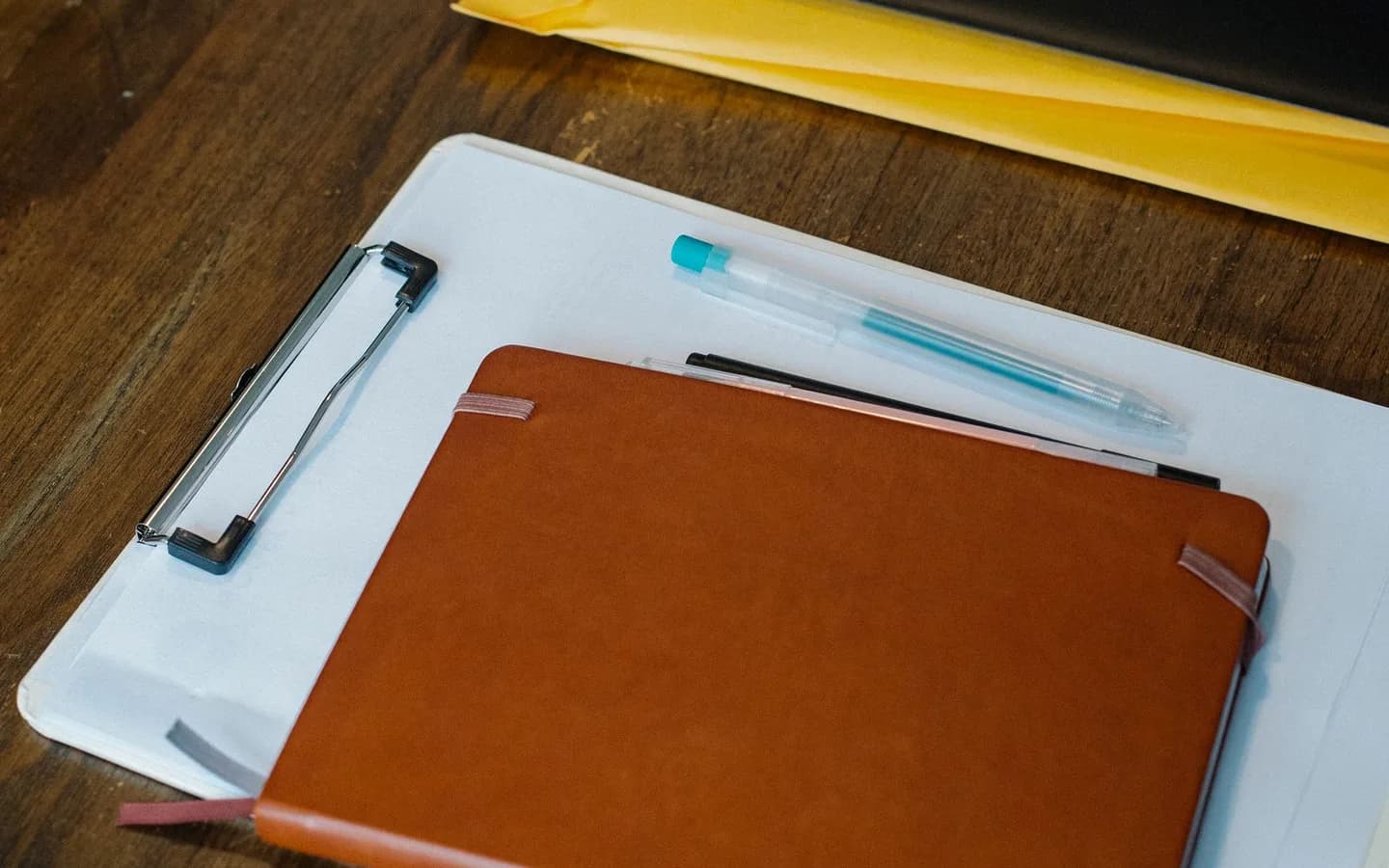 A notebook and clipboard arranged with files on a desk.